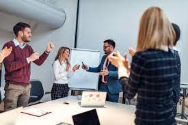 A group of professionals engaged in a discussion beside a whiteboard in an office setting, suggesting collaboration and exchange of ideas for Online Reputation