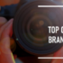 Close-up of a camera lens with the text “TOP CAMERA BRANDS FOR 2024” overlaying the image.